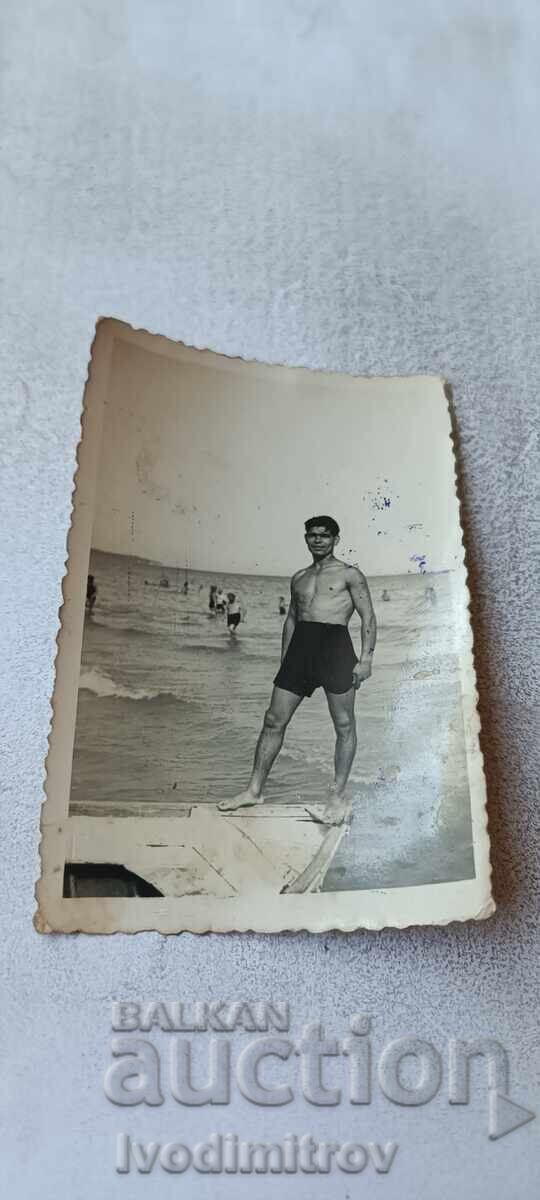 Fotografie Tânăr pe o barcă pe malul mării