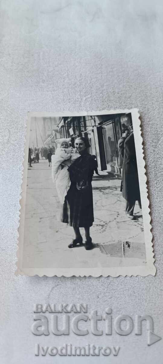 Fotografie Sofia Femeie și bebeluș pe trotuar Fotografie Sofia Femeie și bebeluș pe trotuar