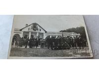 Fotografie vânători și bărbați în fața unei cabane de vânătoare