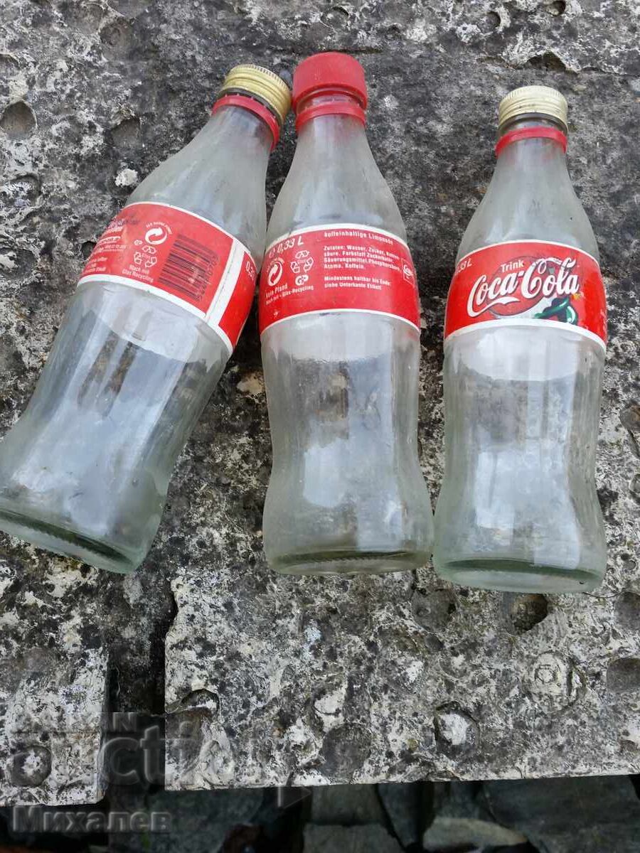 three Coca-Cola glass bottles