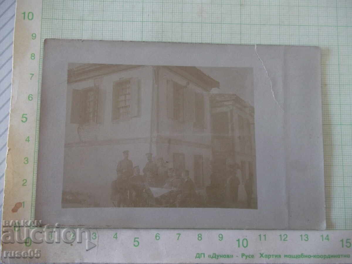 Photo of a group of soldiers around a table in front of an old house