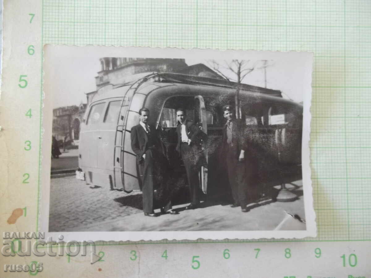 Φωτογραφία τριών ανδρών μπροστά από ένα παλιό λεωφορείο