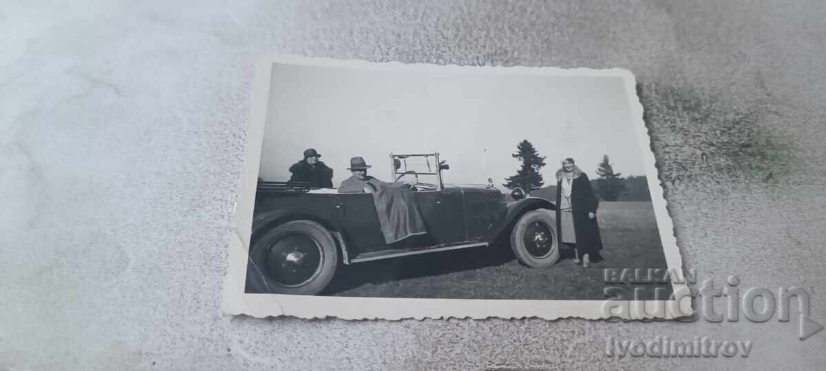 Photo: A man and two women with a vintage car on a ride