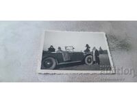 Photo: A man and two women with a vintage car on a ride