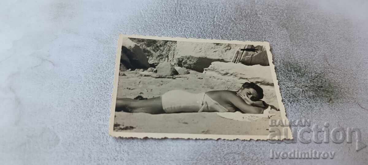 Φωτογραφία Νέα γυναίκα με ρετρό μαγιό ξαπλωμένη στην παραλία Φωτογραφία Νέα γυναίκα με ρετρό μαγιό ξαπλωμένη στην παραλία