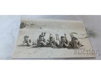 Φωτογραφία Νέοι άνδρες και γυναίκες ξαπλωμένοι με το στομάχι τους στην άμμο