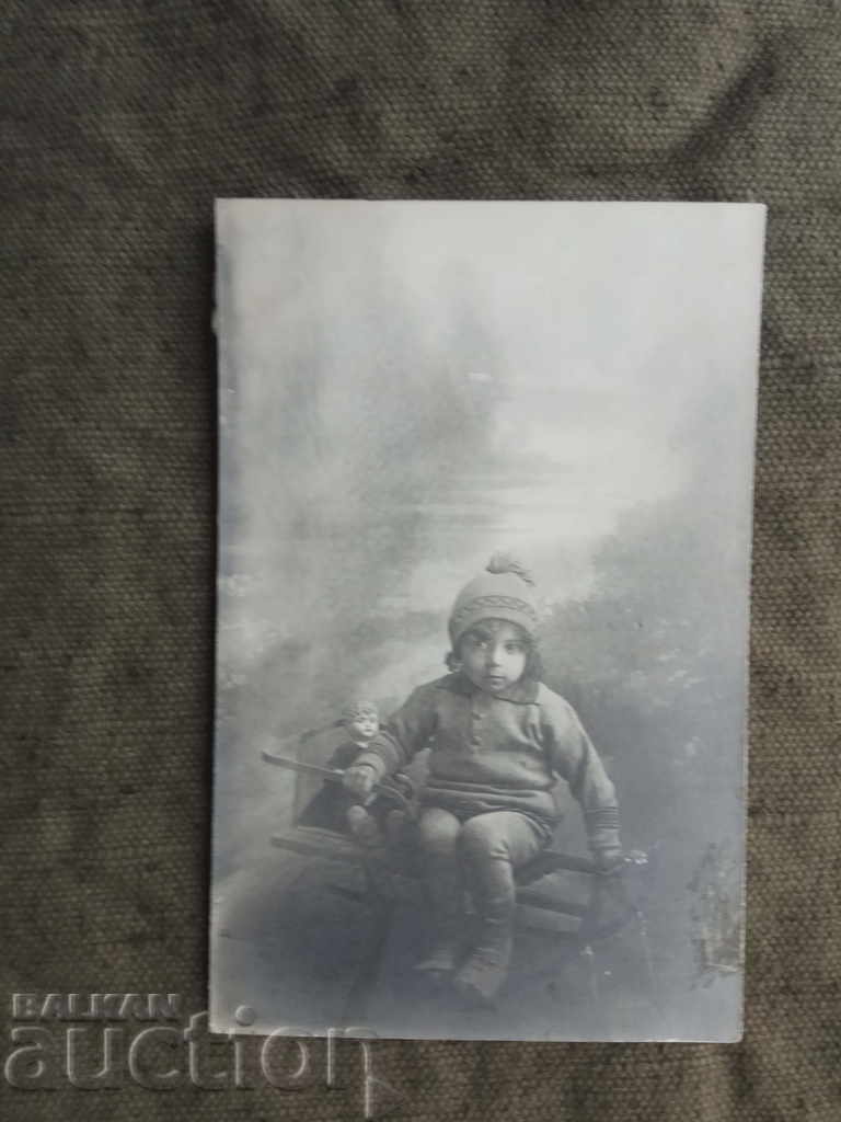 kid on sleigh with doll