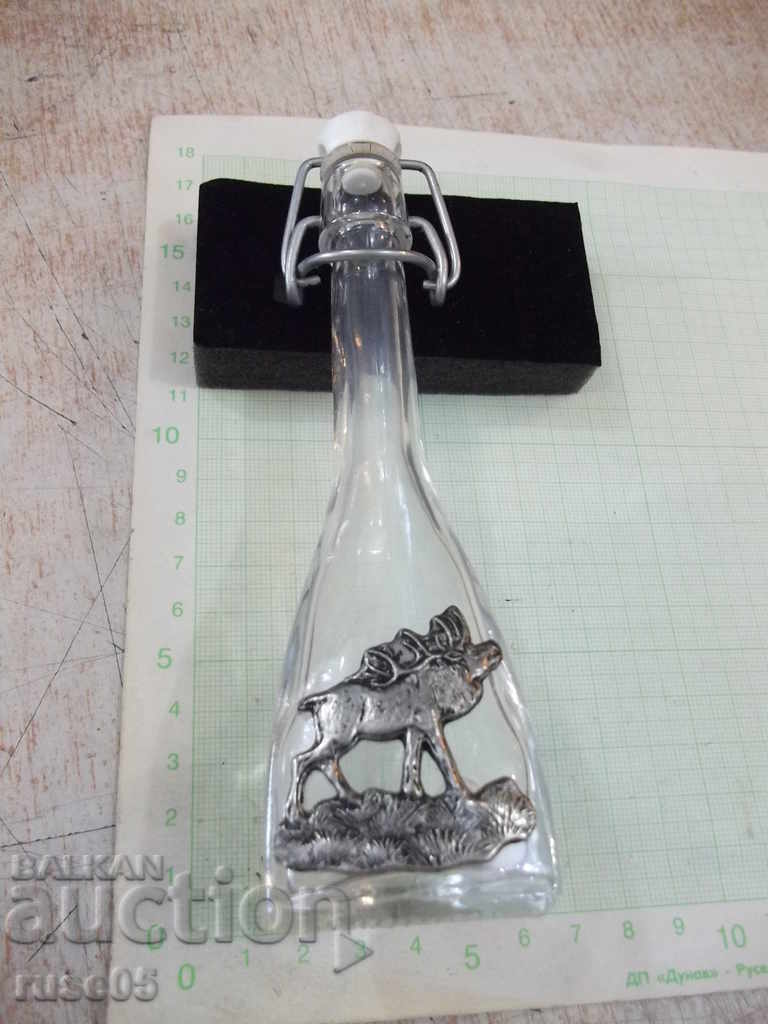Bottle with porcelain flap closure and metal applique