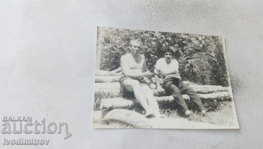 Photo Two men sitting on logs