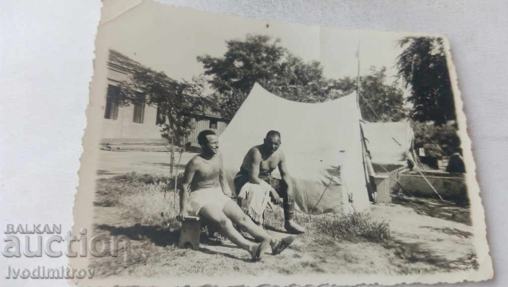 Foto Doi bărbați goi până la brâu lângă corturi