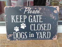 Afișaj metalic care spune că ușa închisă are câini în curte