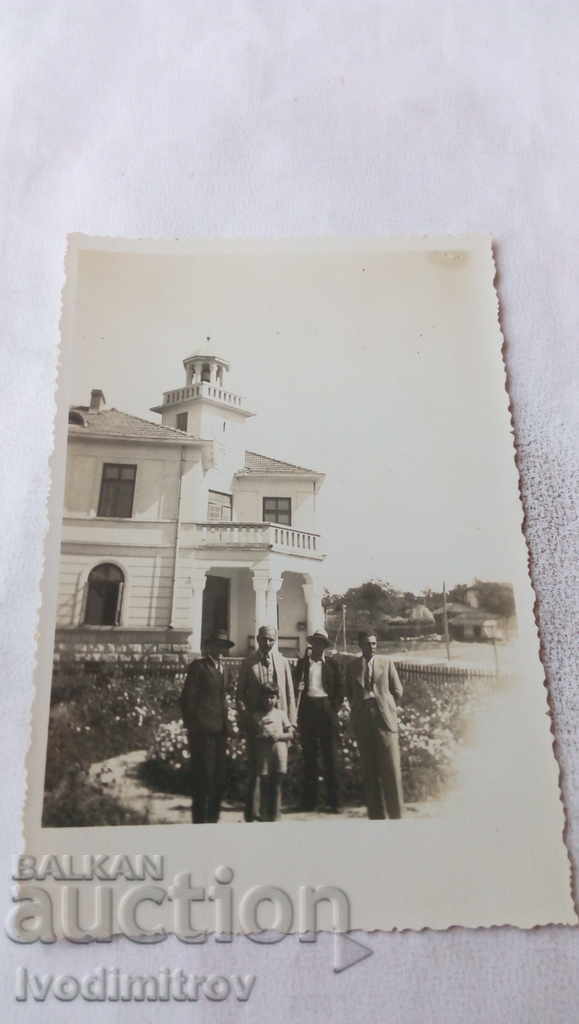 Foto Patru bărbați în fața unei case nou construite, cu clopotniță