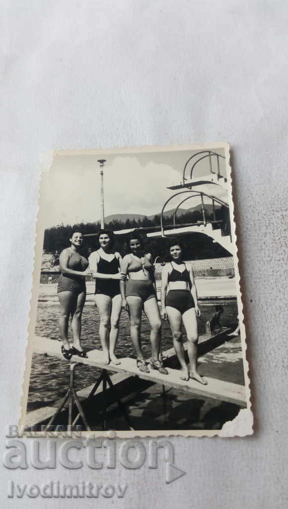 Photo Four women in swimsuits by the pool