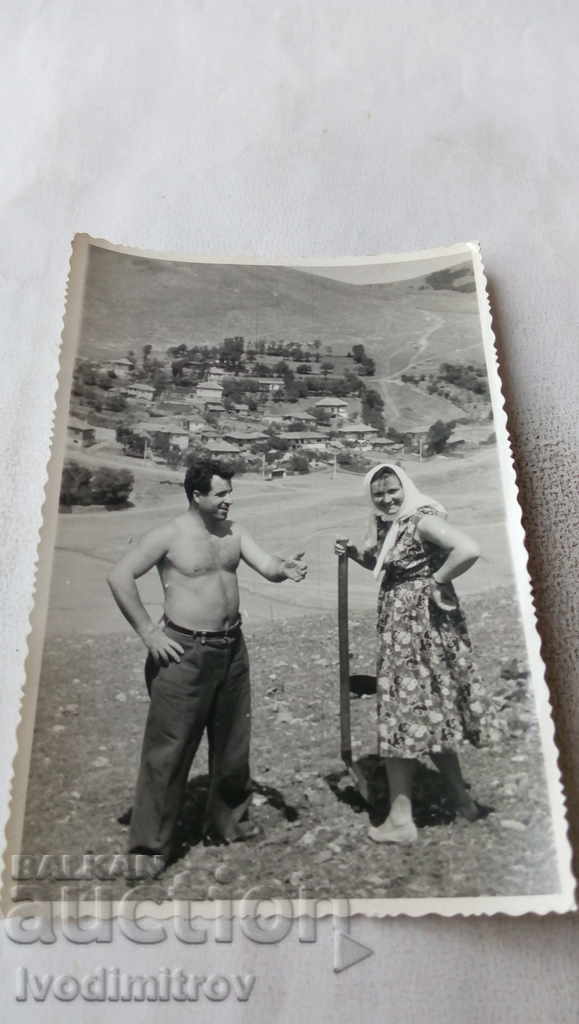 Photo A man naked to the waist and a woman with a shovel