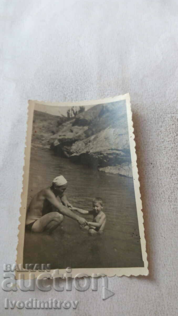 Photo of a boy with his father in the water