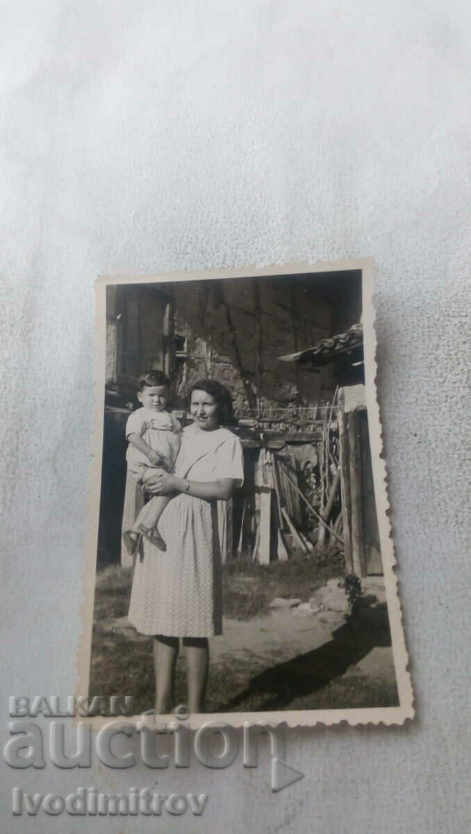 Φωτογραφία Σοφία Μια γυναίκα με ένα αγόρι στην αγκαλιά της στην αυλή ενός σπιτιού