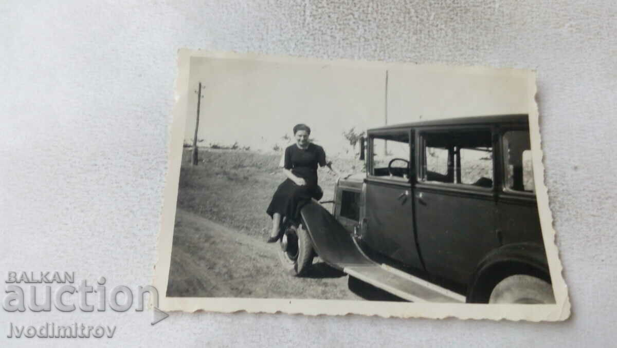 Foto Femeie pe aripa din față a unei mașini retro