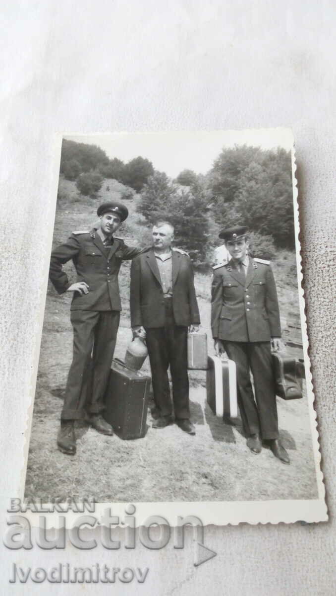 Fotografie cu un bărbat cu o damajana și doi ofițeri cu valize