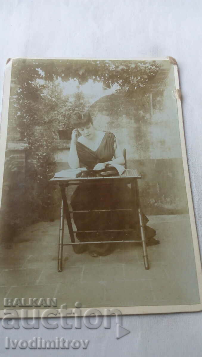 Снимка Млада жена чете списание на двора Картон