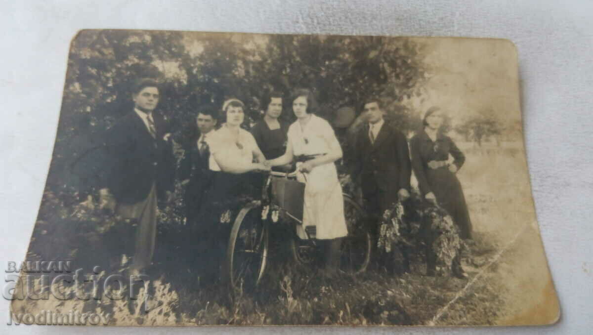 Photo of young men and women and retro bicycle in the park