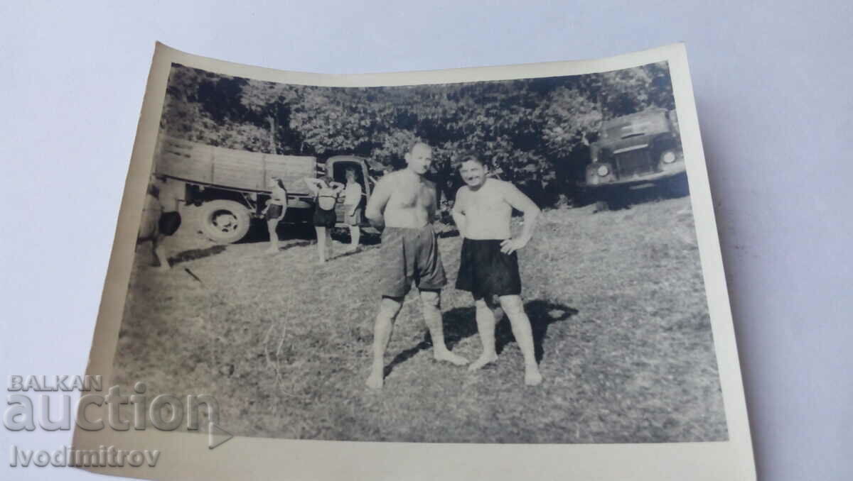 Foto Doi bărbați în pantaloni scurți în fața camioanelor retro