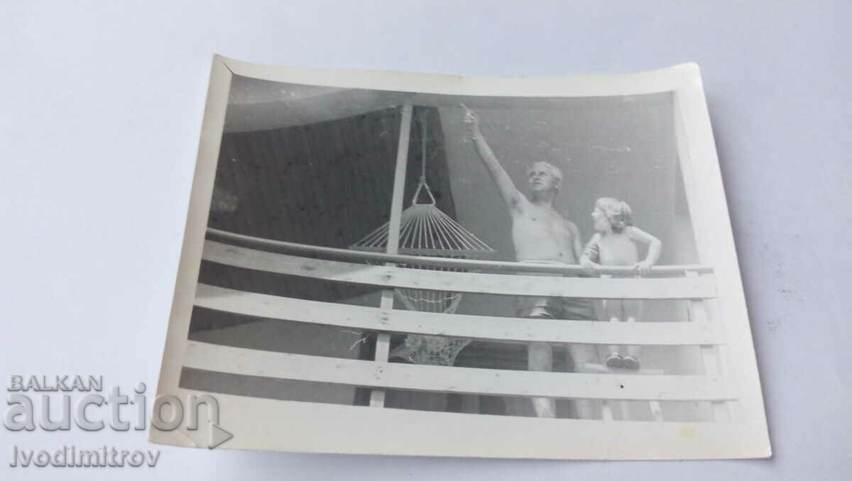 Foto Bărbat în pantaloni scurți și un băiat pe balcon