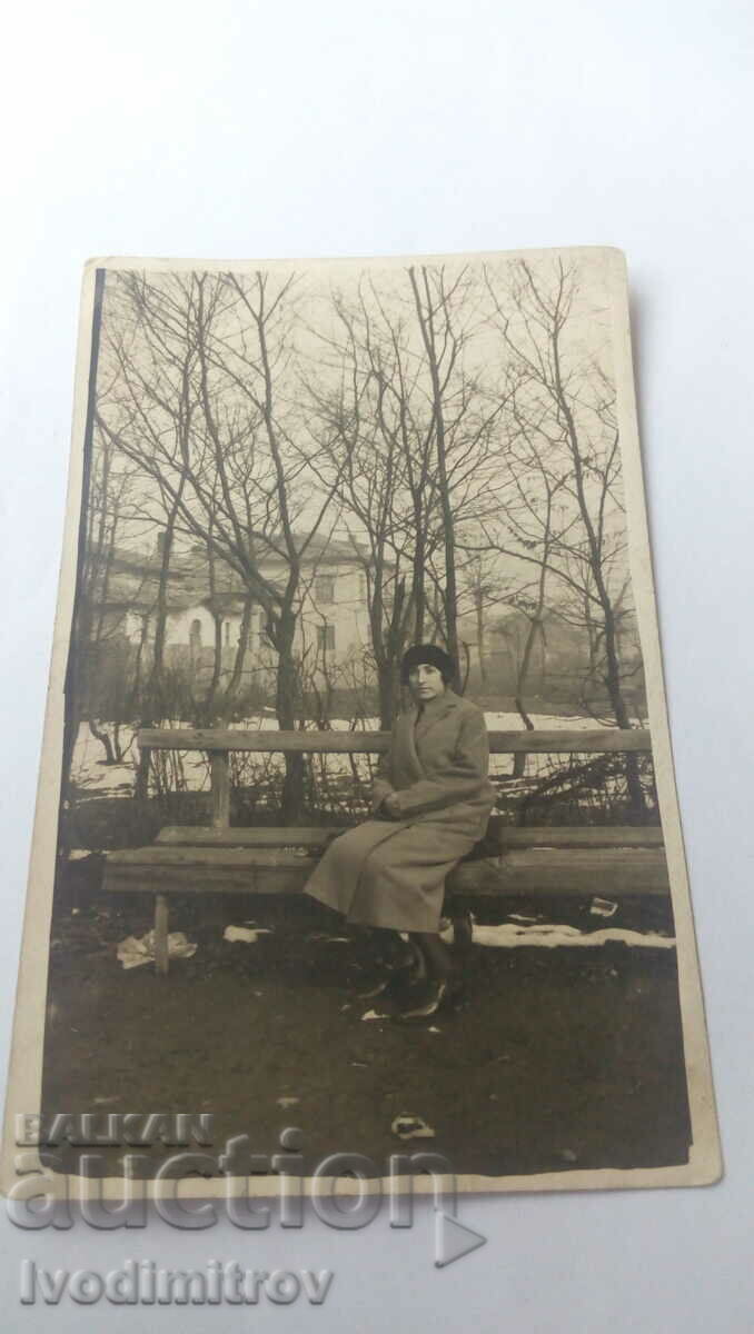 Снимка Жена със зимно палто на пейка