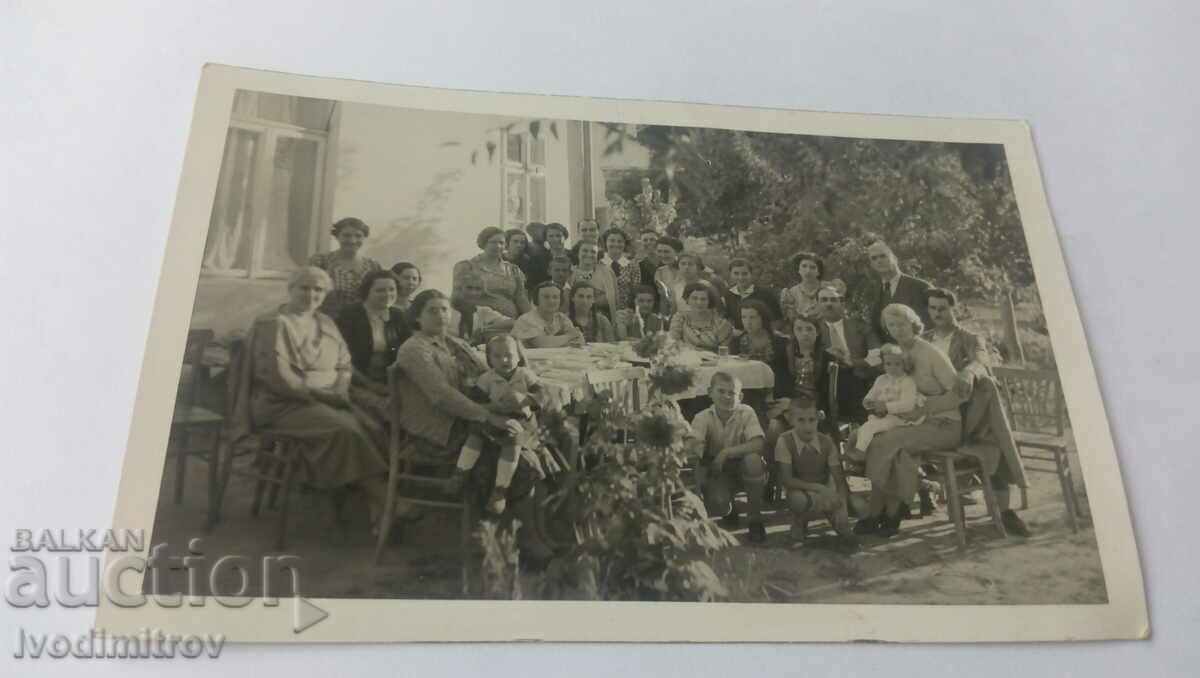 Foto Bărbați, femei și copii în jurul unei mese în curte