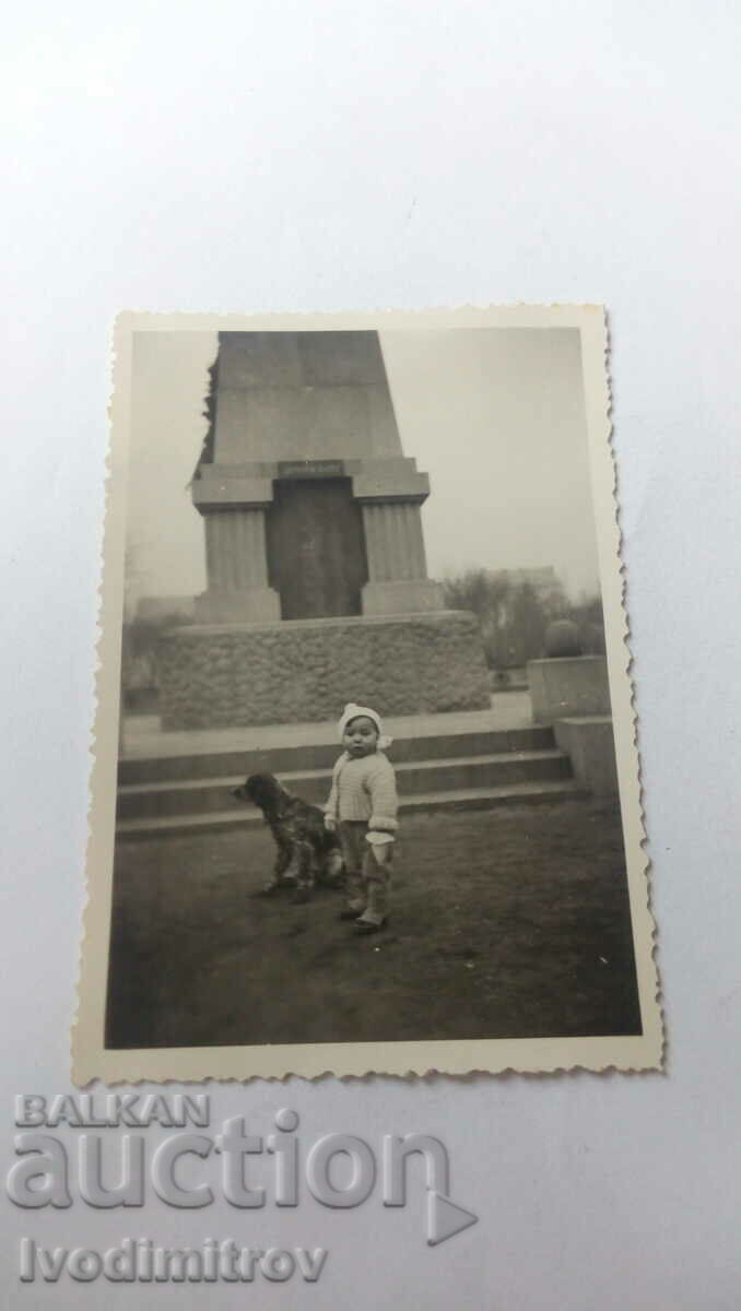 Fotografie Fetiță și câine în fața unui monument