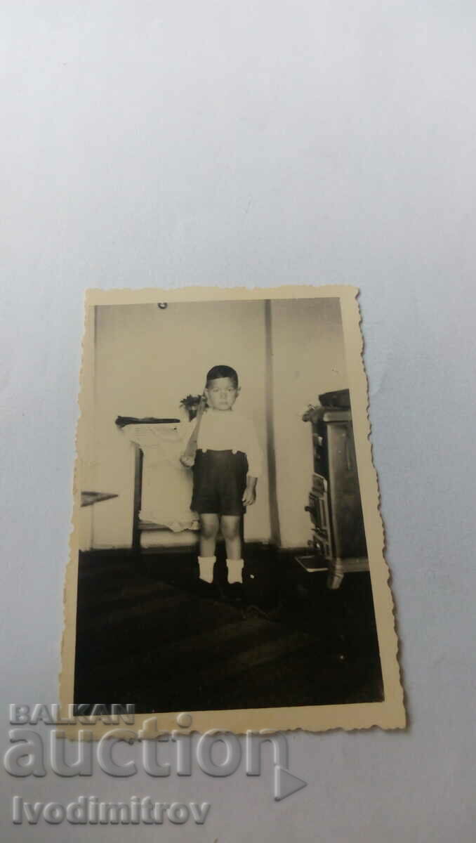 Foto Băiețel într-o cameră lângă o sobă cu lemne
