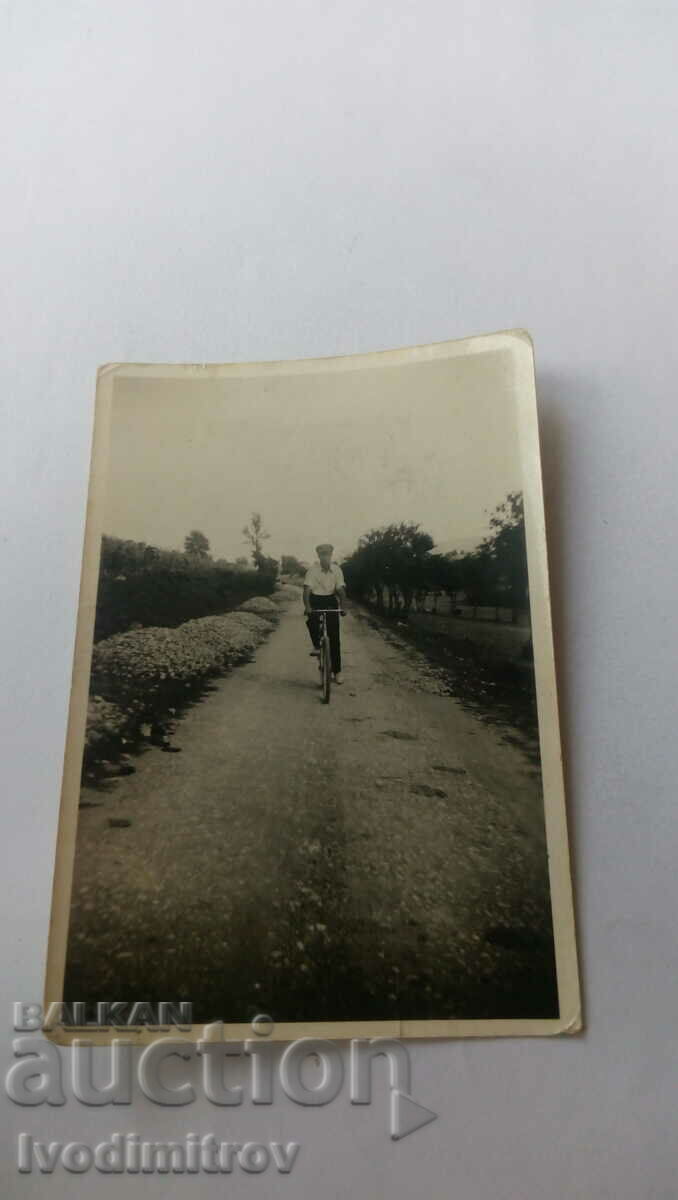 Fotografie cu un bărbat cu o bicicletă retro pe drum
