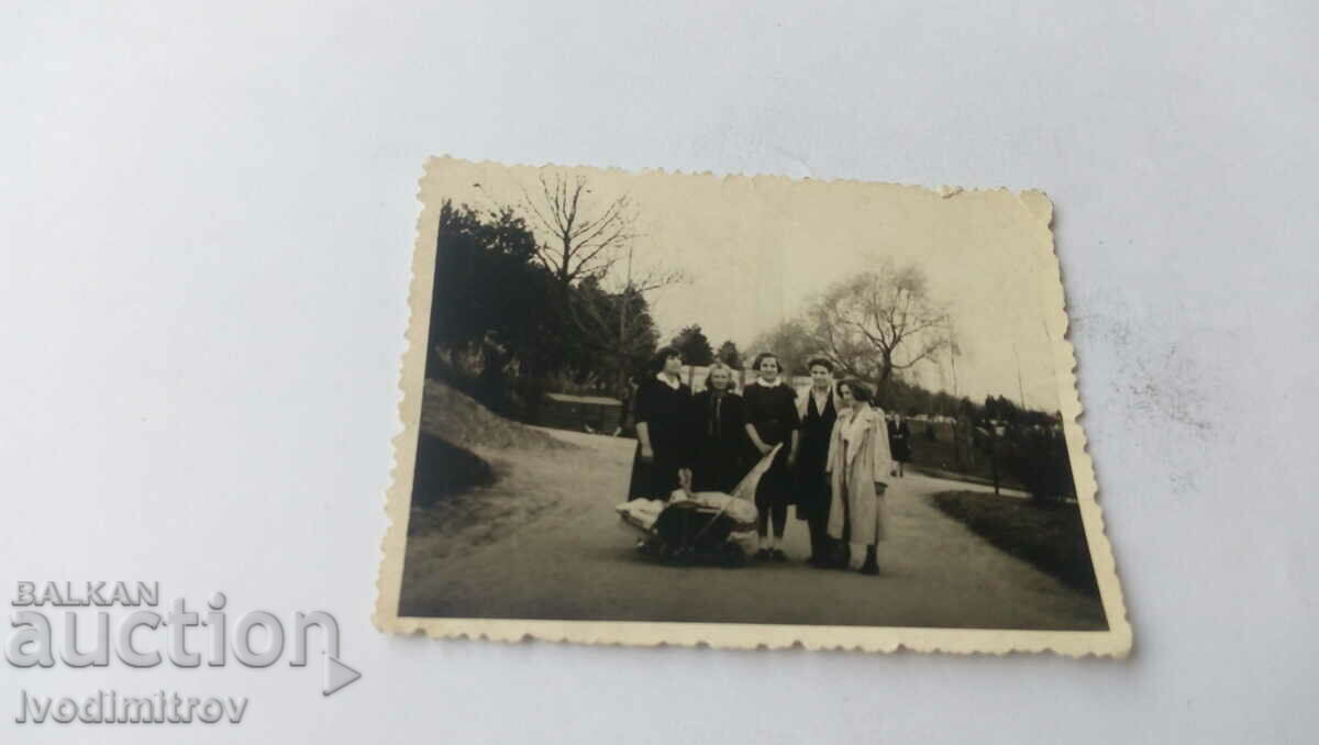 Photo A man and four women with a retro stroller in the park