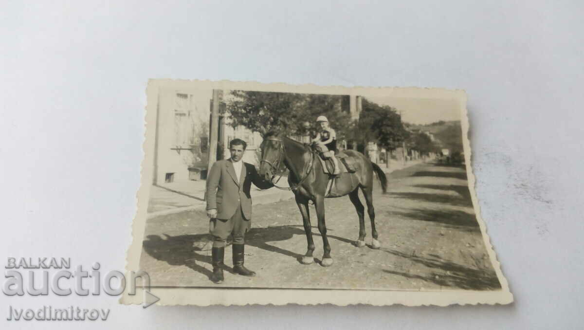 Fotografie cu un bărbat și un băiețel cu un cal pe stradă