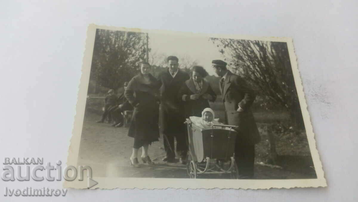 Foto Bărbați, femei și bebeluși într-un cărucior retro