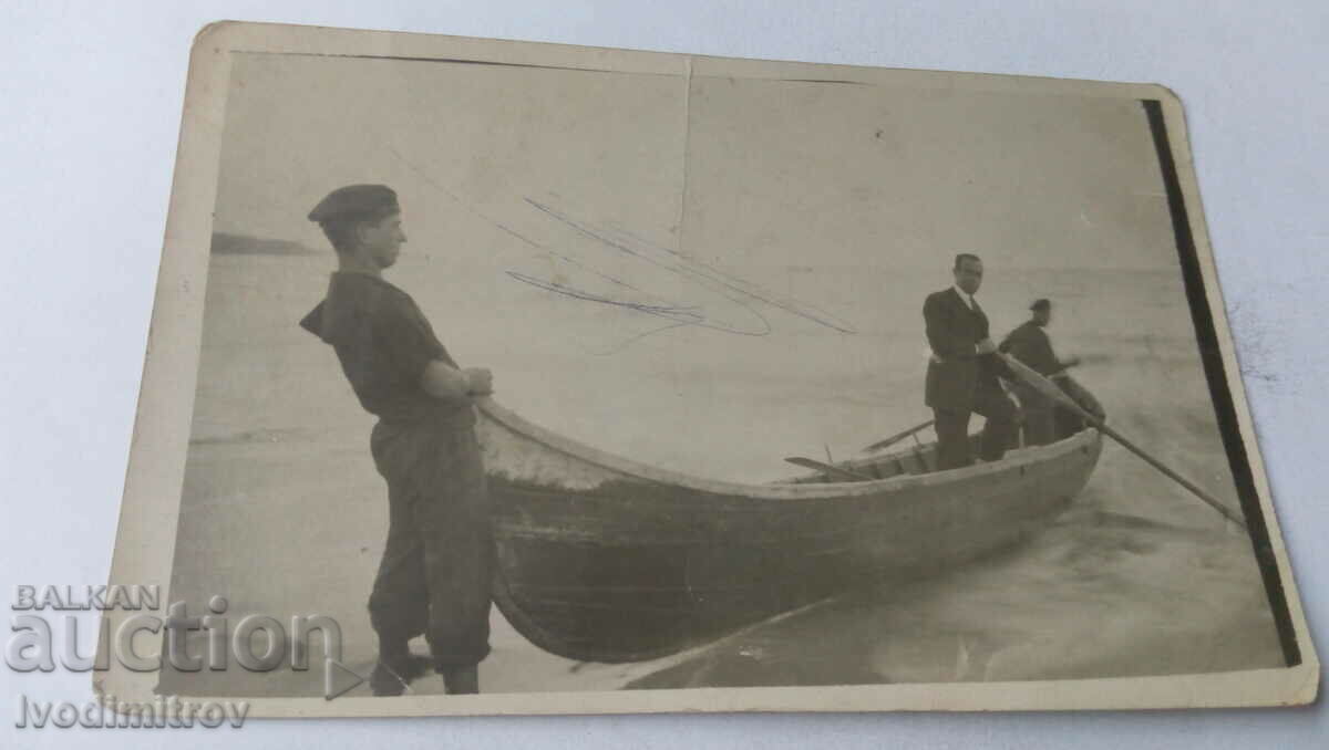 Foto Trei bărbați într-o barcă pe plajă