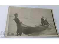 Снимка Трима мъже с лодка на брега на морето
