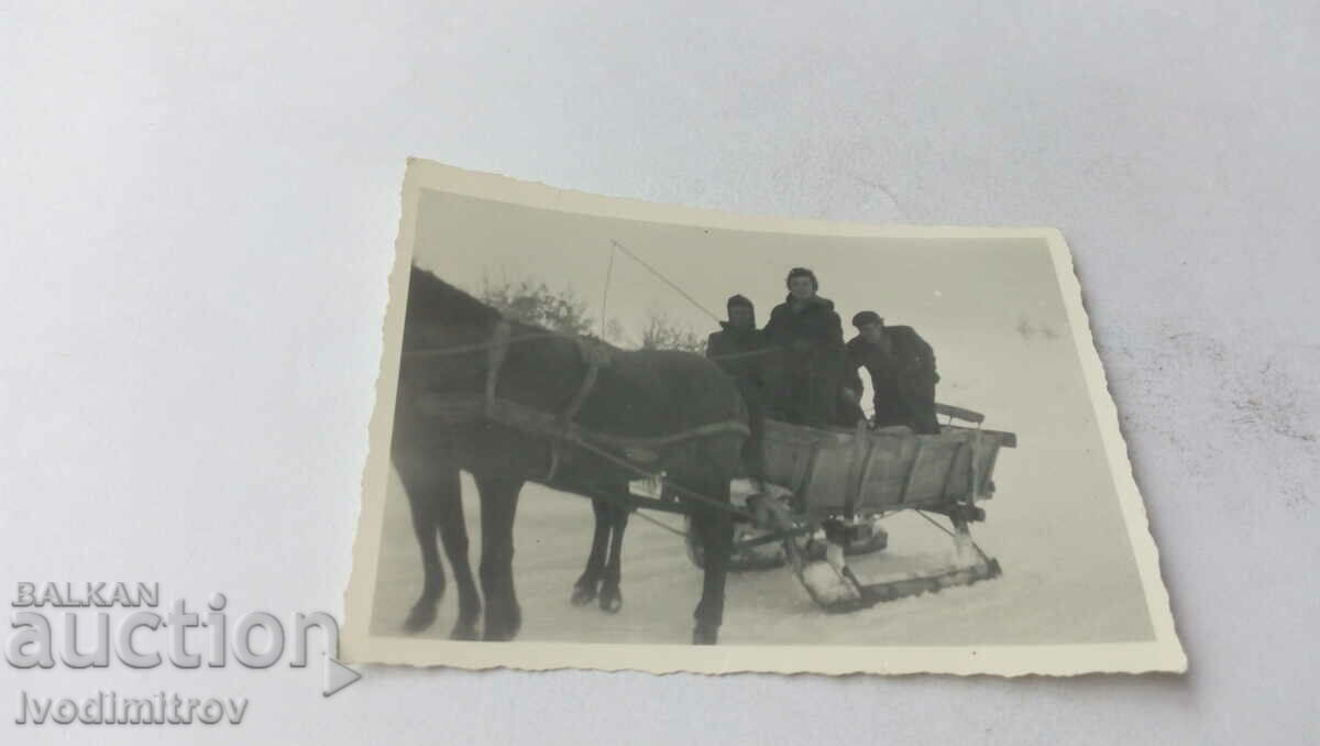 Photo A woman and two men with a sled in the winter