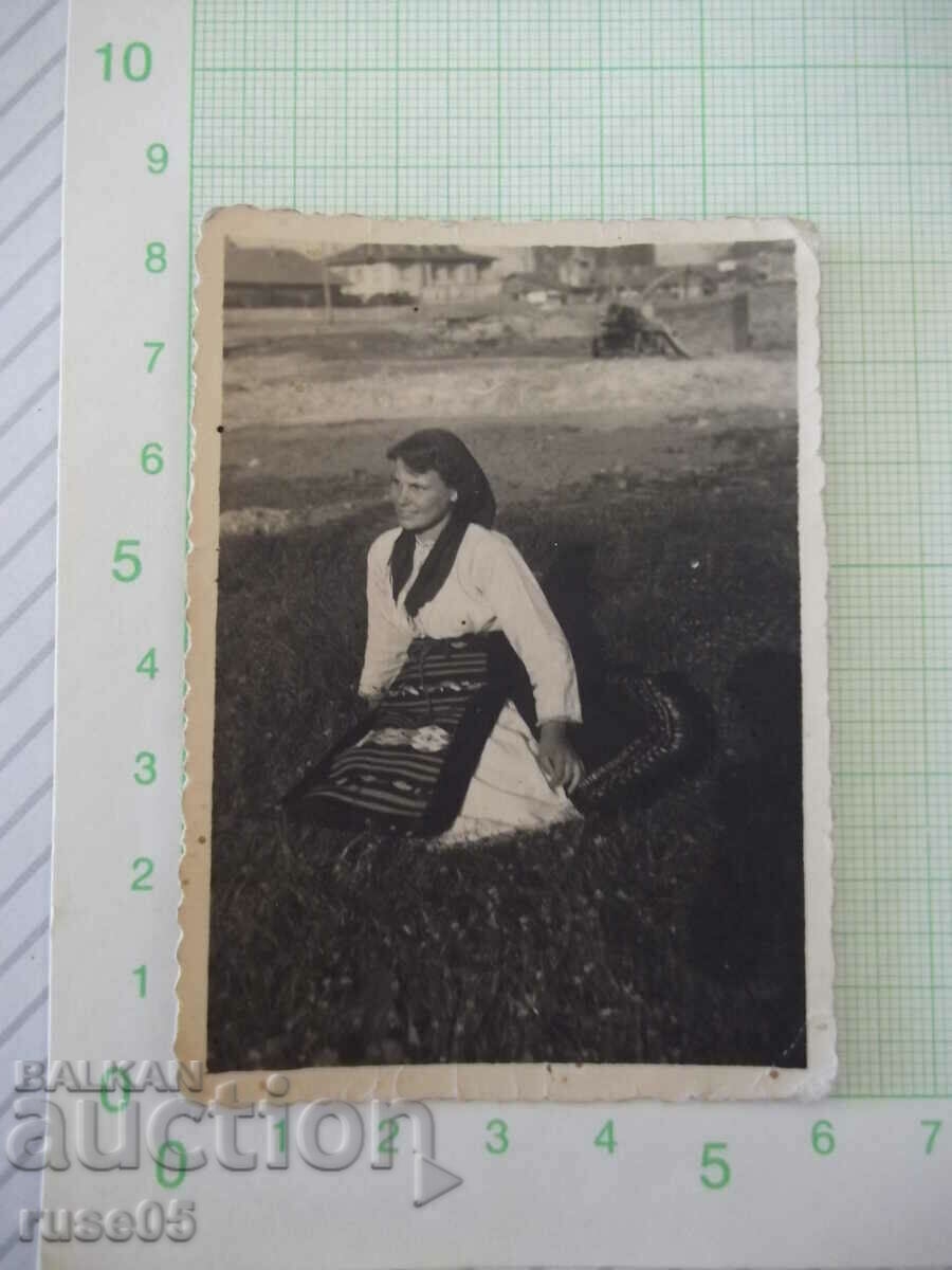 Снимка стара на жена в носия седнала на поляната