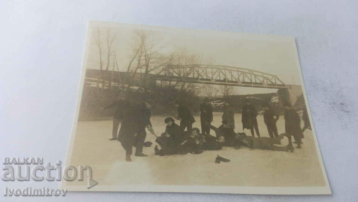 Φωτογραφία Νεολαία σε ένα παγωμένο ποτάμι μπροστά από μια σιδηροδρομική γέφυρα