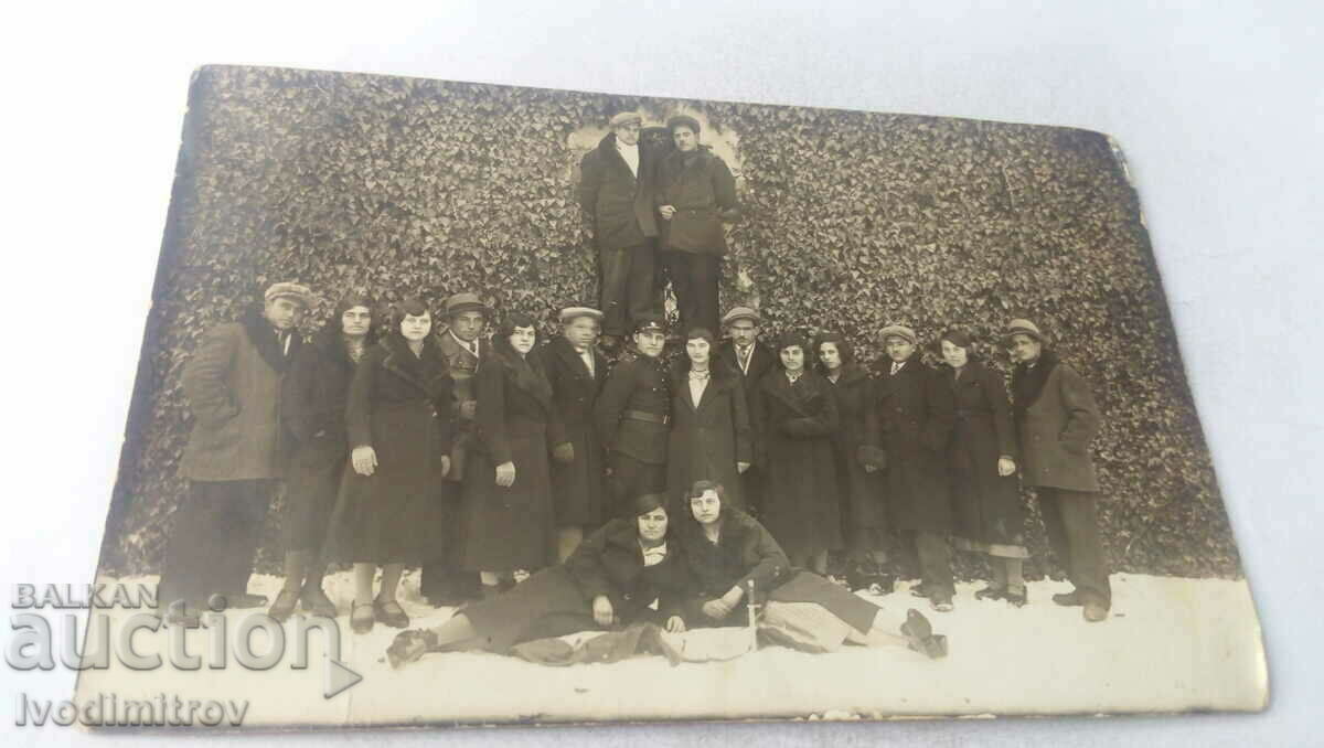 Picture Men and women in front of a wall overgrown with boxwood