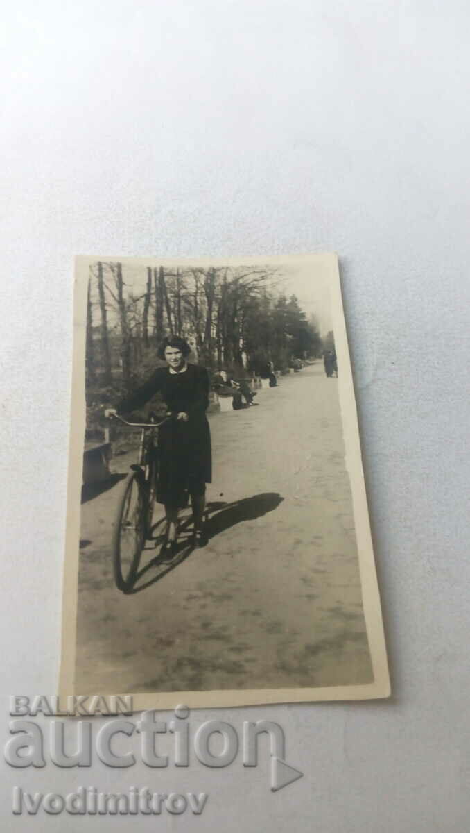 Φωτογραφία Νεαρή γυναίκα με ένα εκλεκτής ποιότητας ποδήλατο στο πάρκο