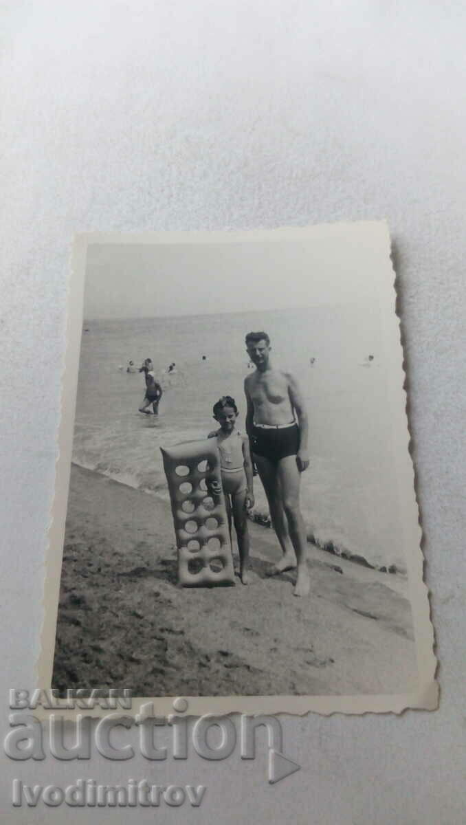 Φωτογραφία Ένας άντρας και ένα αγόρι με ένα λαστιχένιο στρώμα στην παραλία