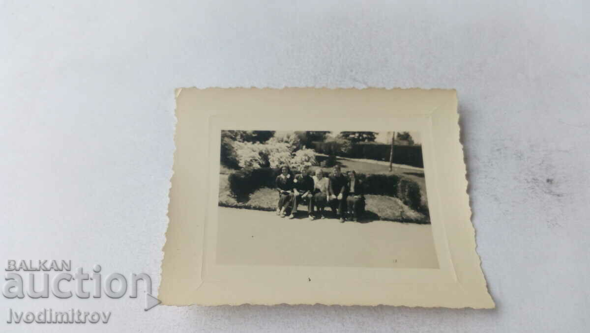 Photo A young man and four girls on a park bench