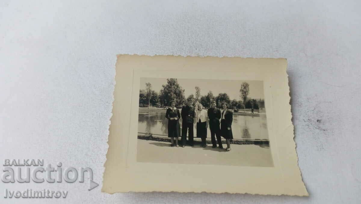 Photo A young man and four girls in front of a lake in the park