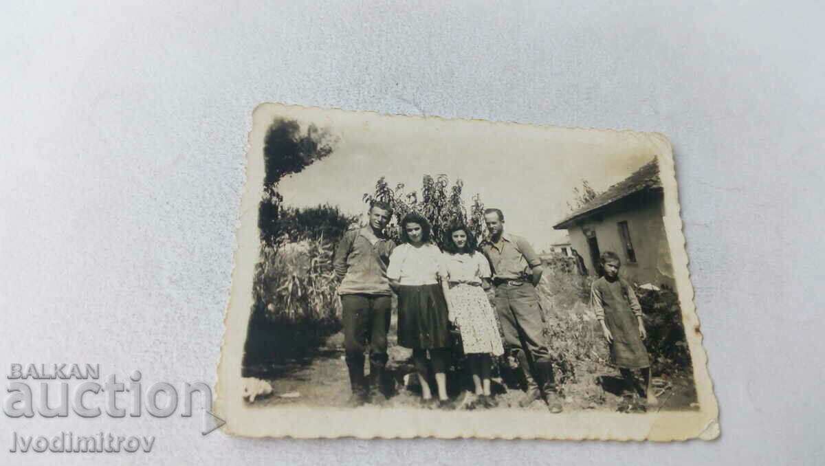 Foto Doi bărbați, două tinere și o fată în fața unei case vechi