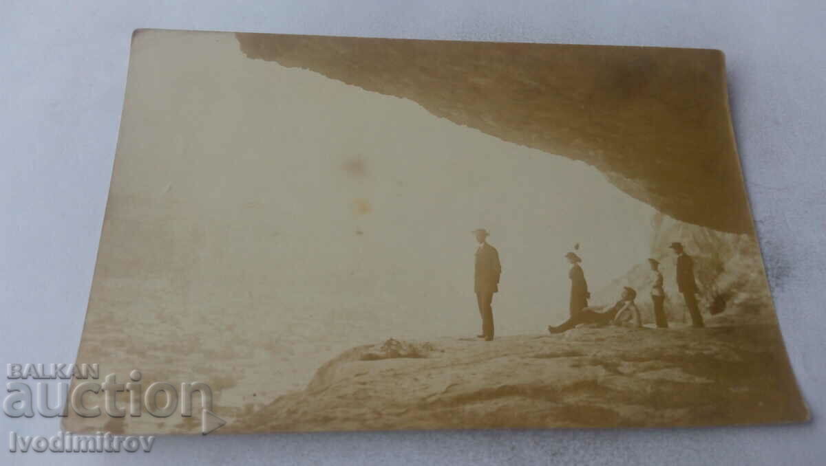 Photo A woman and four men at the entrance of a cave