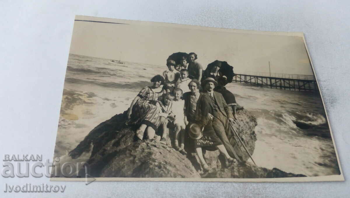 Fotografie Bărbați, femei și copii pe o stâncă lângă mare
