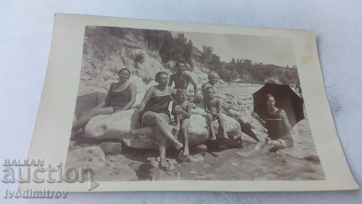 Fotografie Bărbat femei și doi băieți pe pietre pe plajă