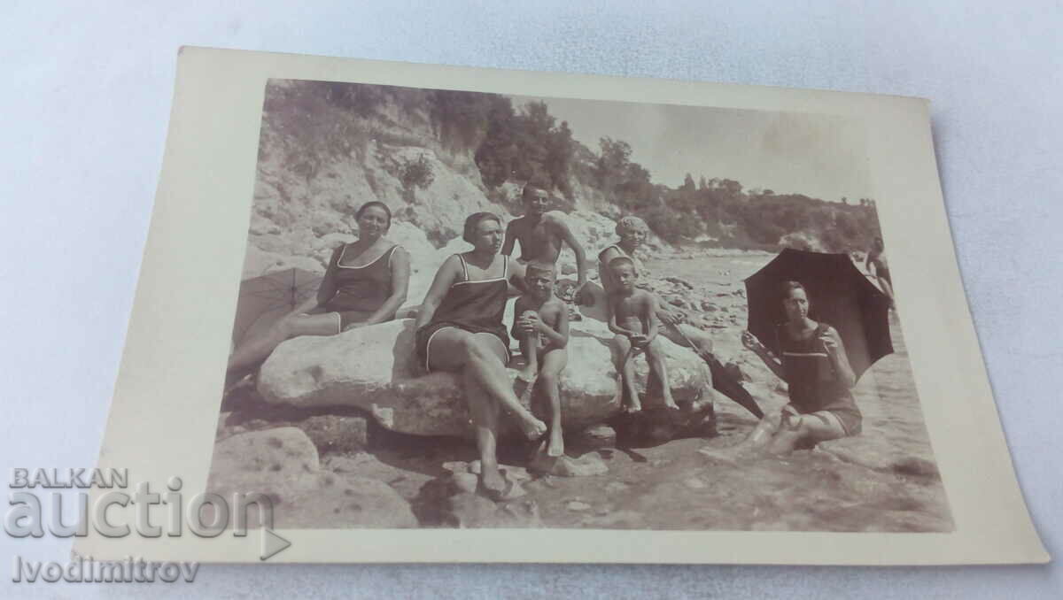 Φωτογραφία Άνδρας γυναίκες και δύο αγόρια σε πέτρες στην παραλία