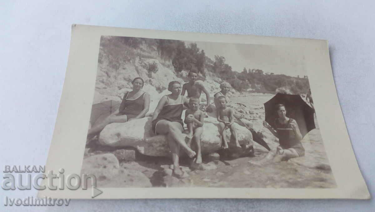 Φωτογραφία Άνδρας γυναίκες και δύο αγόρια σε πέτρες στην παραλία